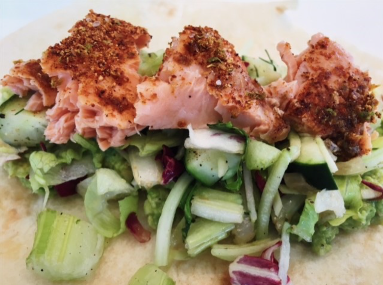 One salmon taco on a bed of lettuce and cucumber