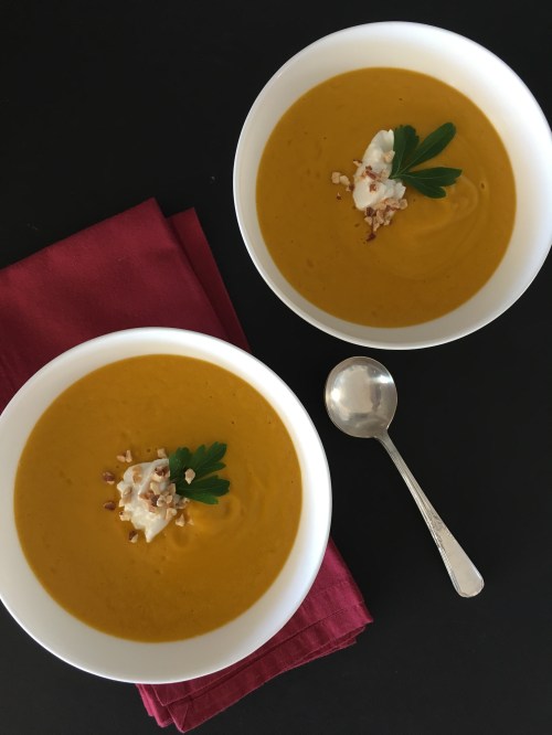 Two white bowls filled with roast carrot and cumin soup