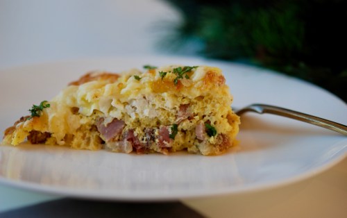 Slice of ham and cheese frittata on a white plate